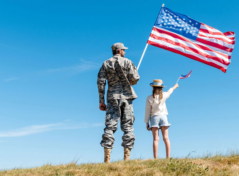 soldier holding an american flag next to a child