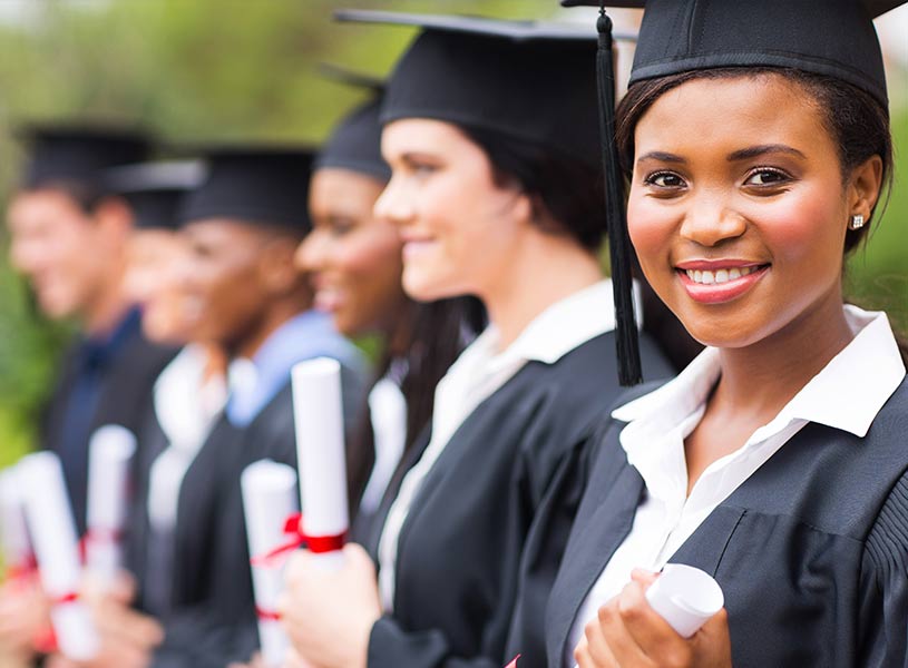 graduates in caps and gowns holding diplomas at a graduation ceremony.